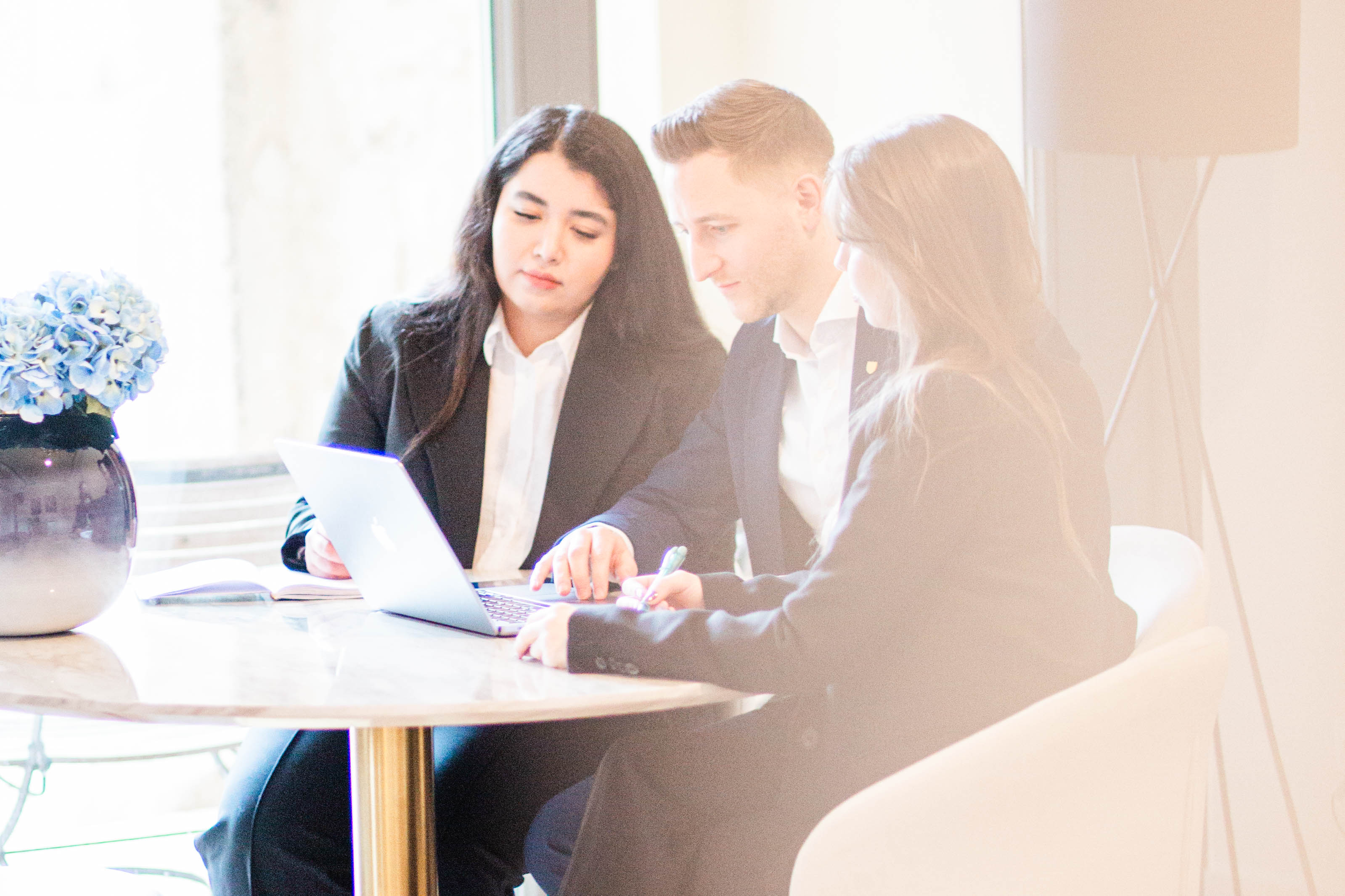 Das Team versammelt sich zu einer Besprechung, während der Laptop im Mittelpunkt steht.