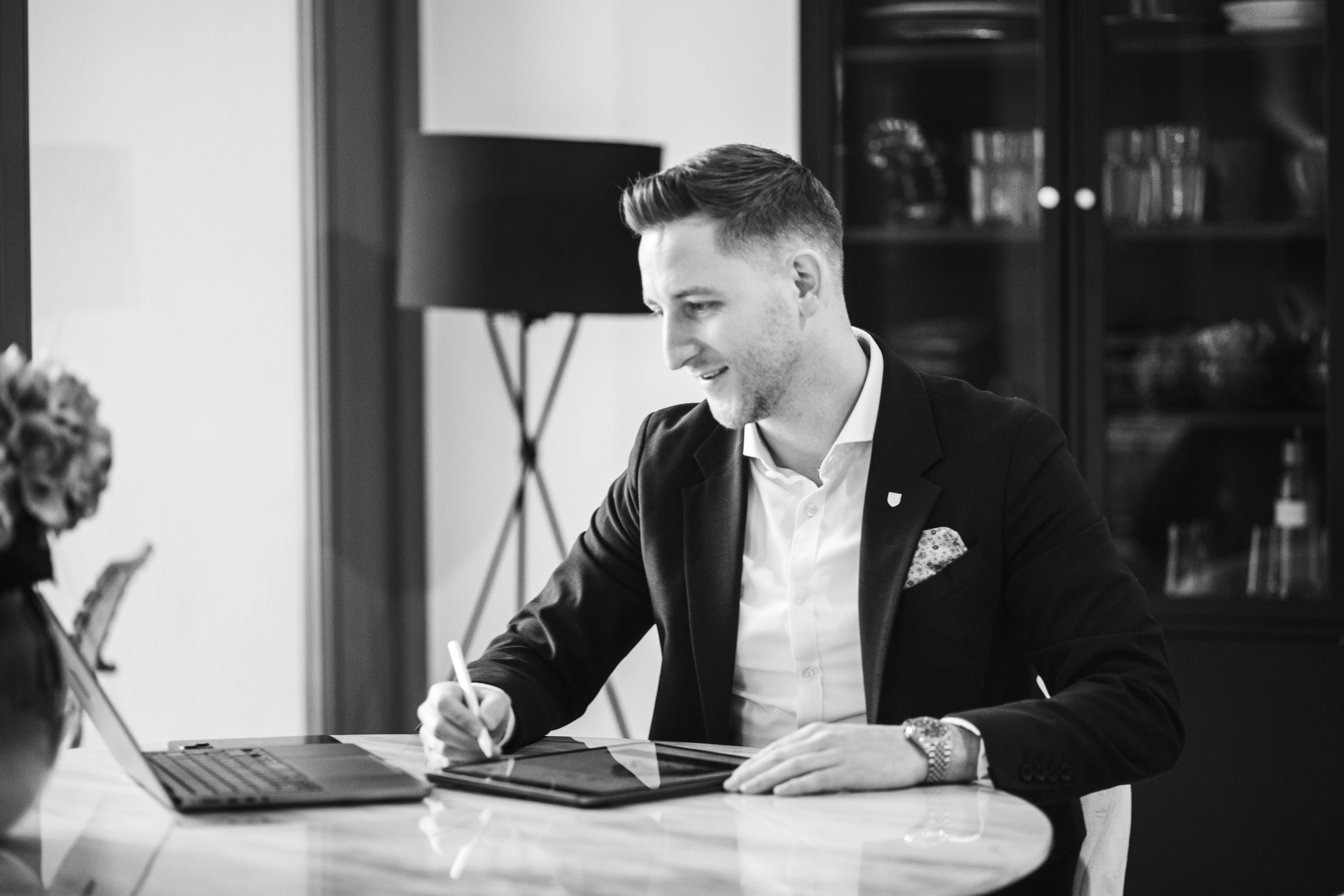 Johannes macht sich Notizen, während vor ihm ein Laptop geöffnet ist.